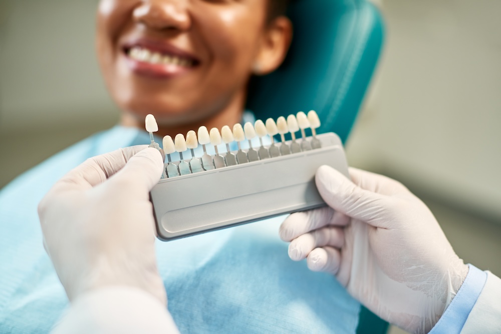 Blurry photo of patient on dentistry chair while denstist decides which size of cap will fit patient's teeth best for dental crowns near Waxhaw