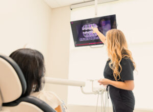 A female Dogwood Dental Spa provider shows a female patient an X-ray of her teeth. This X-ray allows the provider to see if the patient needs dentures in Waxhaw to combat tooth loss.